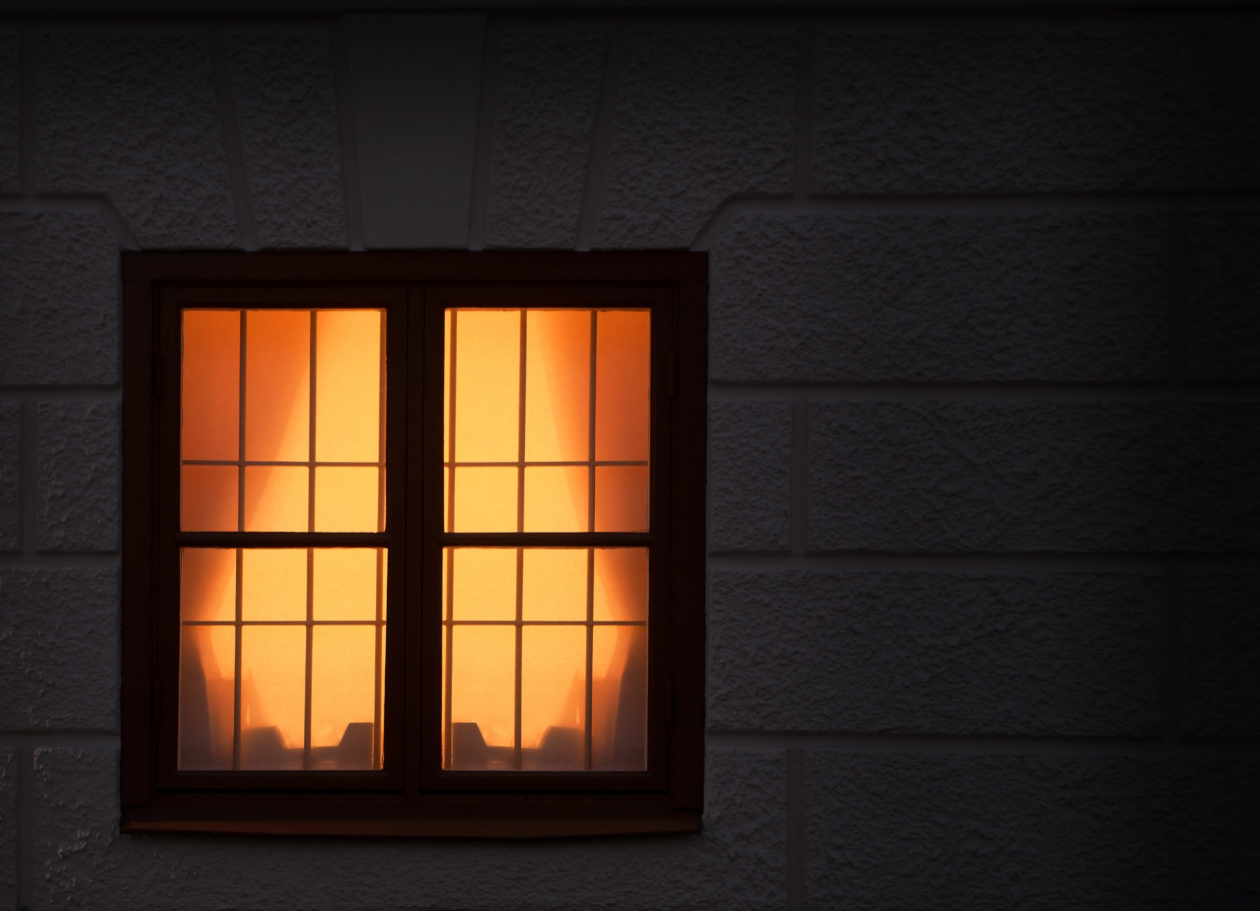 Ein einzelnes beleuchtetes Fenster in einer dunklen Hauswand